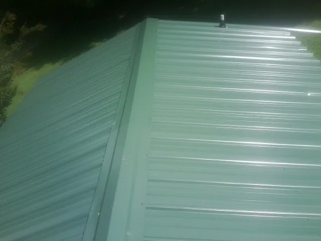 New green metal panels meeting at the ridge of a roof — Flat Roof Repair work by our crew in Midvale